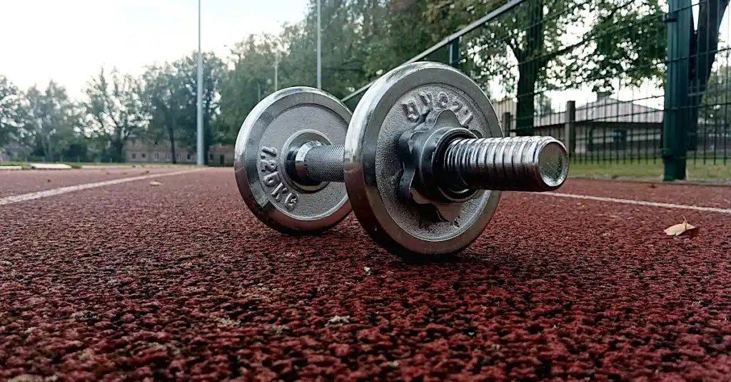 Adjustable dumbbell on outdoor running track used for a dumbbell workout program