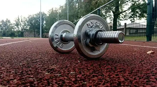 Adjustable dumbbell on outdoor running track used for a dumbbell workout program
