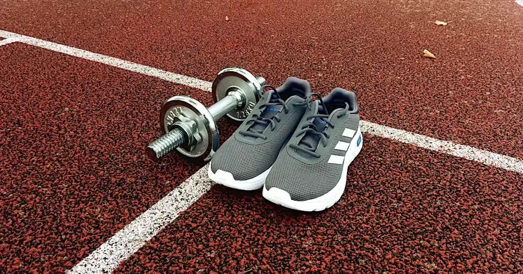 Strength vs cardio after 40 — running shoes and dumbbells on a track